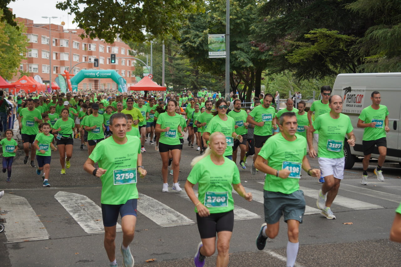 Participantes corriendo en la carrera contra el cáncer en Palencia, vestidos de verde.