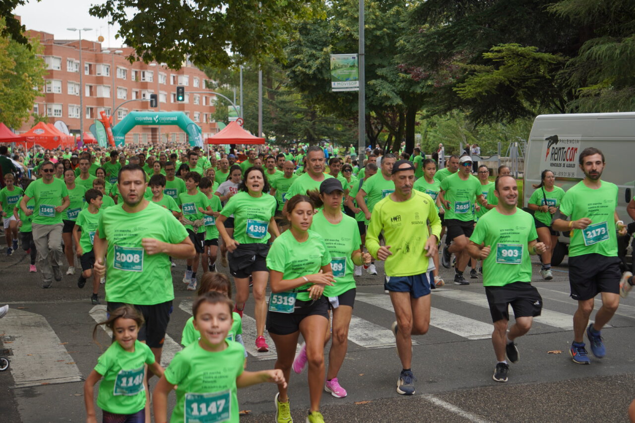 Participantes corriendo en la Carrera contra el Cáncer en Palencia, todos vestidos de verde.