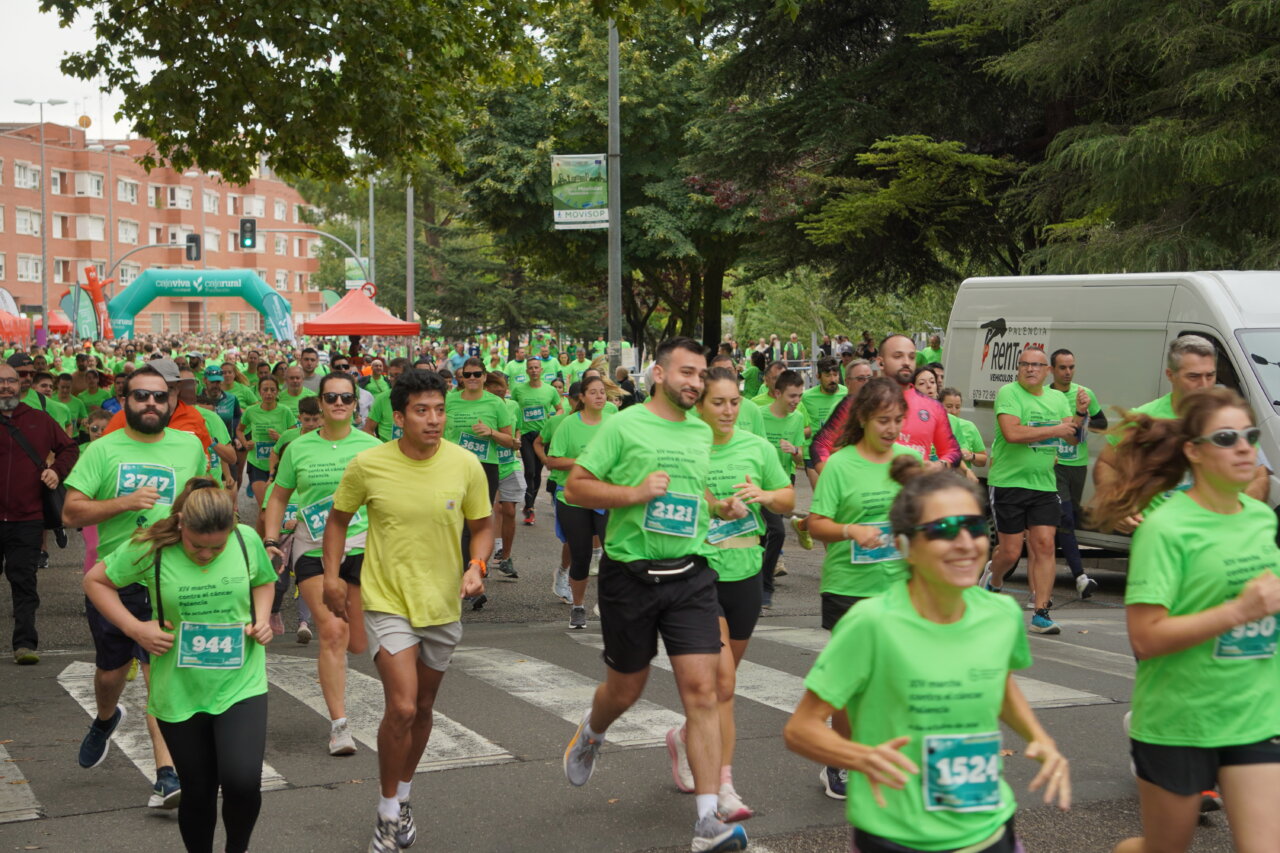 Participantes corriendo en la Carrera contra el Cáncer en Palencia con camisetas verdes.