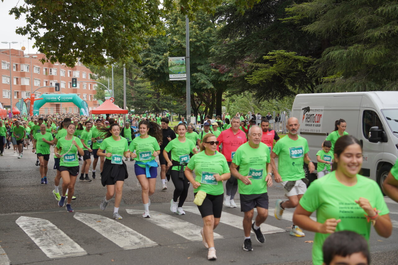 Participantes corriendo en la carrera contra el cáncer en Palencia, todos vestidos de verde.