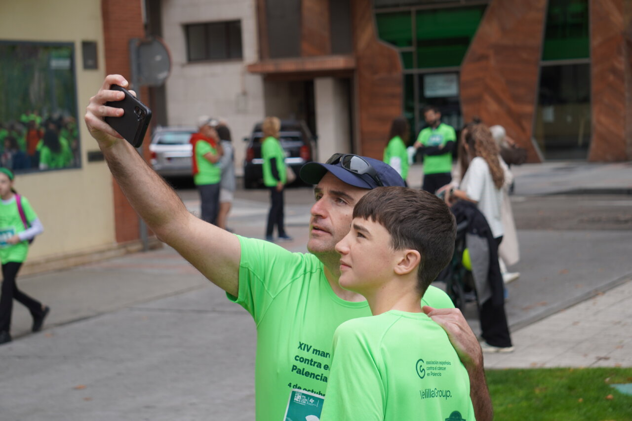 Hombre y niño posando para una selfie en la carrera contra el cáncer en Palencia