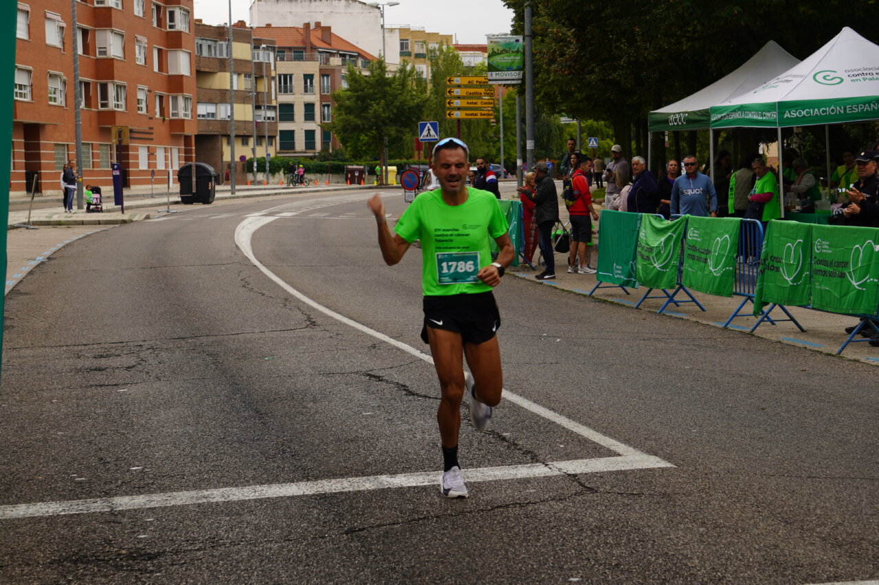 Corredor en la Carrera contra el Cáncer en Palencia, vistiendo camiseta verde.