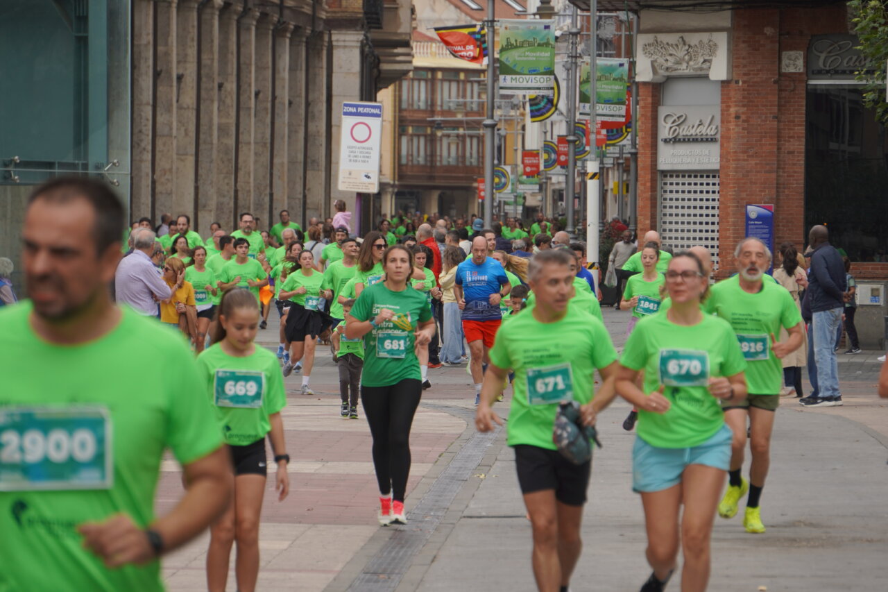 Participantes corriendo en la carrera contra el cáncer en Palencia, vestidos de verde.