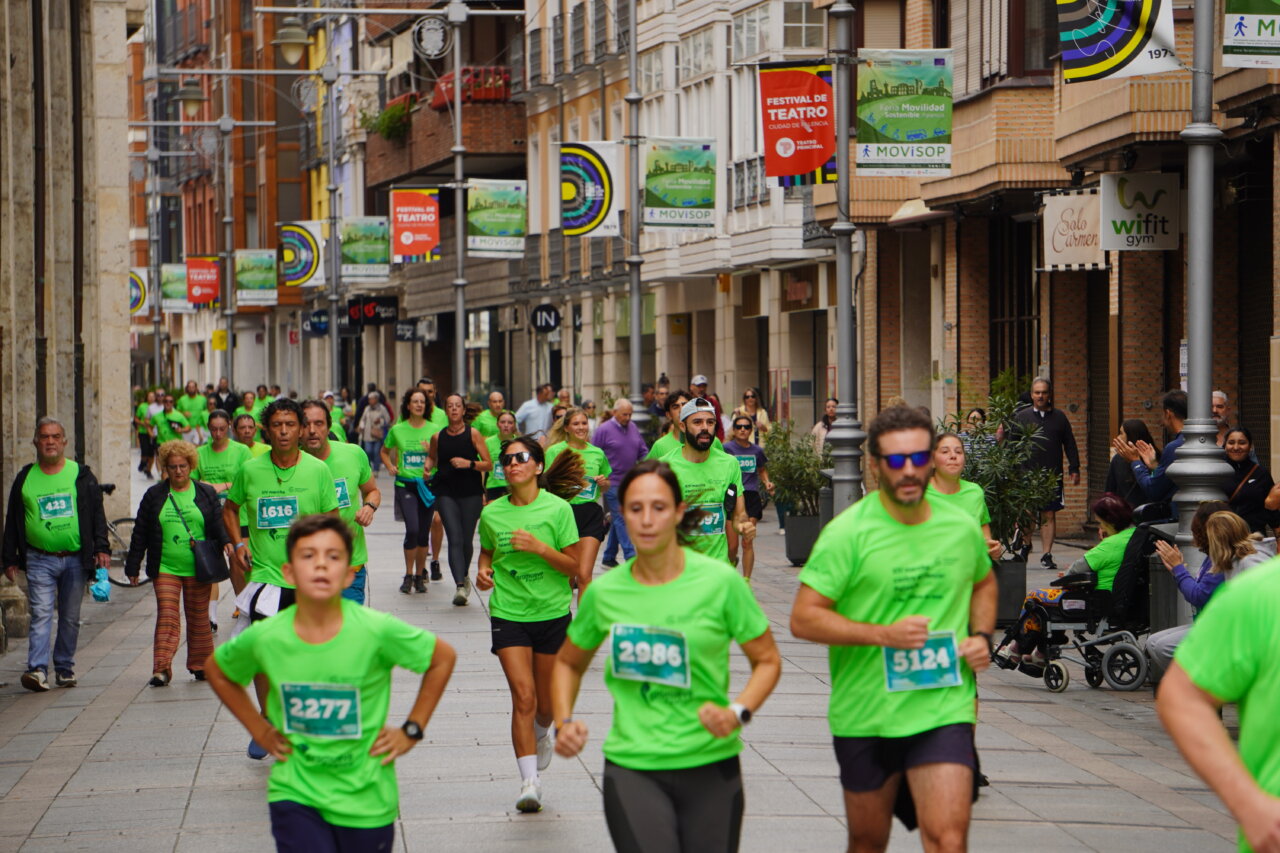 Participantes corriendo en la Carrera contra el Cáncer en Palencia, todos vestidos de verde.