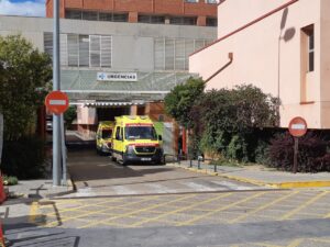 Acceso señalizado de Urgencias con dos ambulancias estacionadas bajo una marquesina.