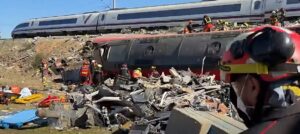Restos de trenes tras un accidente ferroviario, con equipos de emergencia trabajando entre los vagones.
