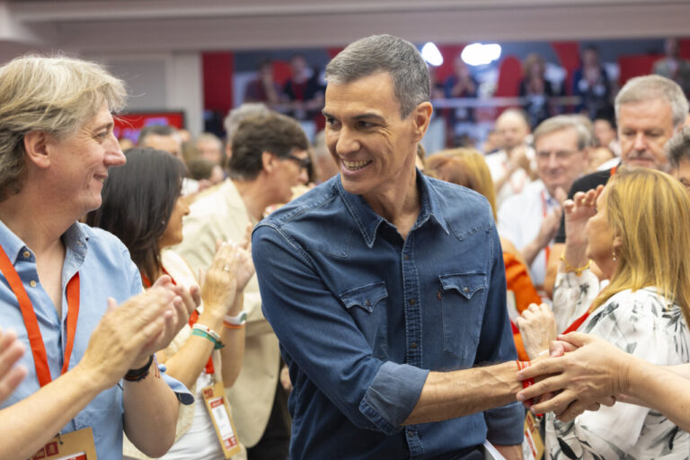 Evento político con personas aplaudiendo y sonriendo en un ambiente de campaña