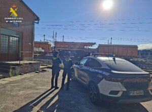 Dos agentes de la Guardia Civil junto a un coche patrulla en una estación ferroviaria.