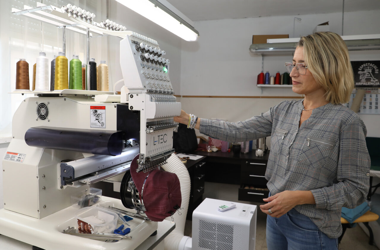 Mujer operando una máquina de bordado en taller de moda sostenible