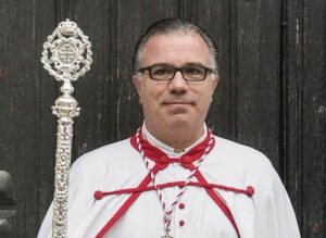 Ángel Alfonso Martínez con vestimenta de cofrade y cetro en mano