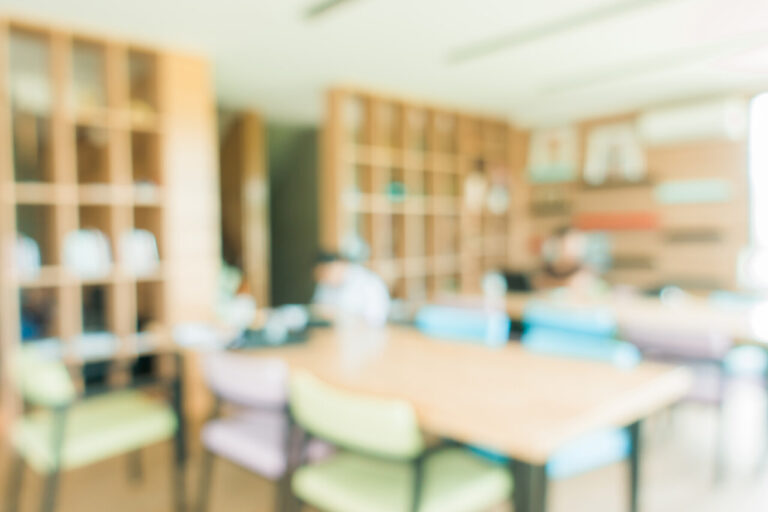 Aula vacía con mesas y sillas en un fondo borroso