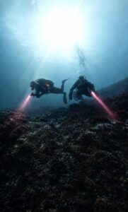 Dos buceadores explorando el fondo marino con linternas