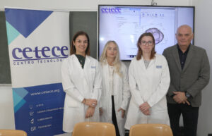 Cuatro personas posan junto a un cartel de CETECE y una pantalla con gráficos.