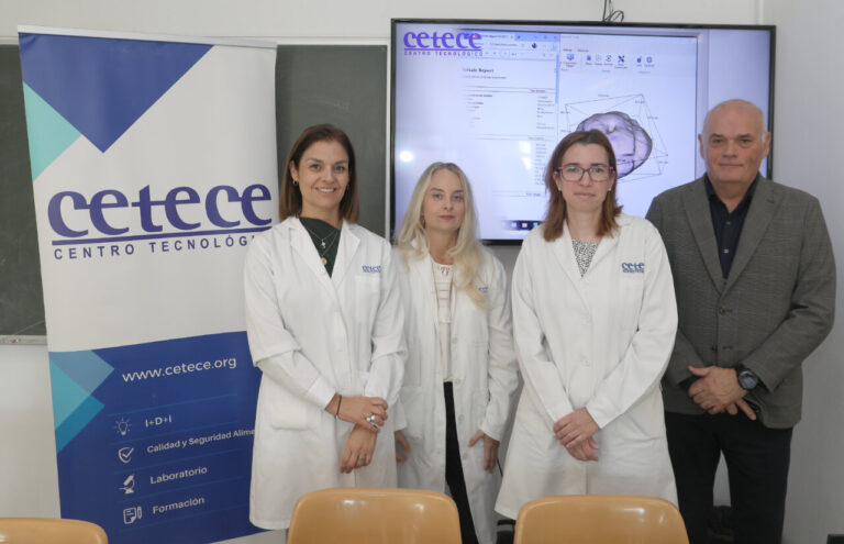 Cuatro personas posan junto a un cartel de CETECE y una pantalla con gráficos.