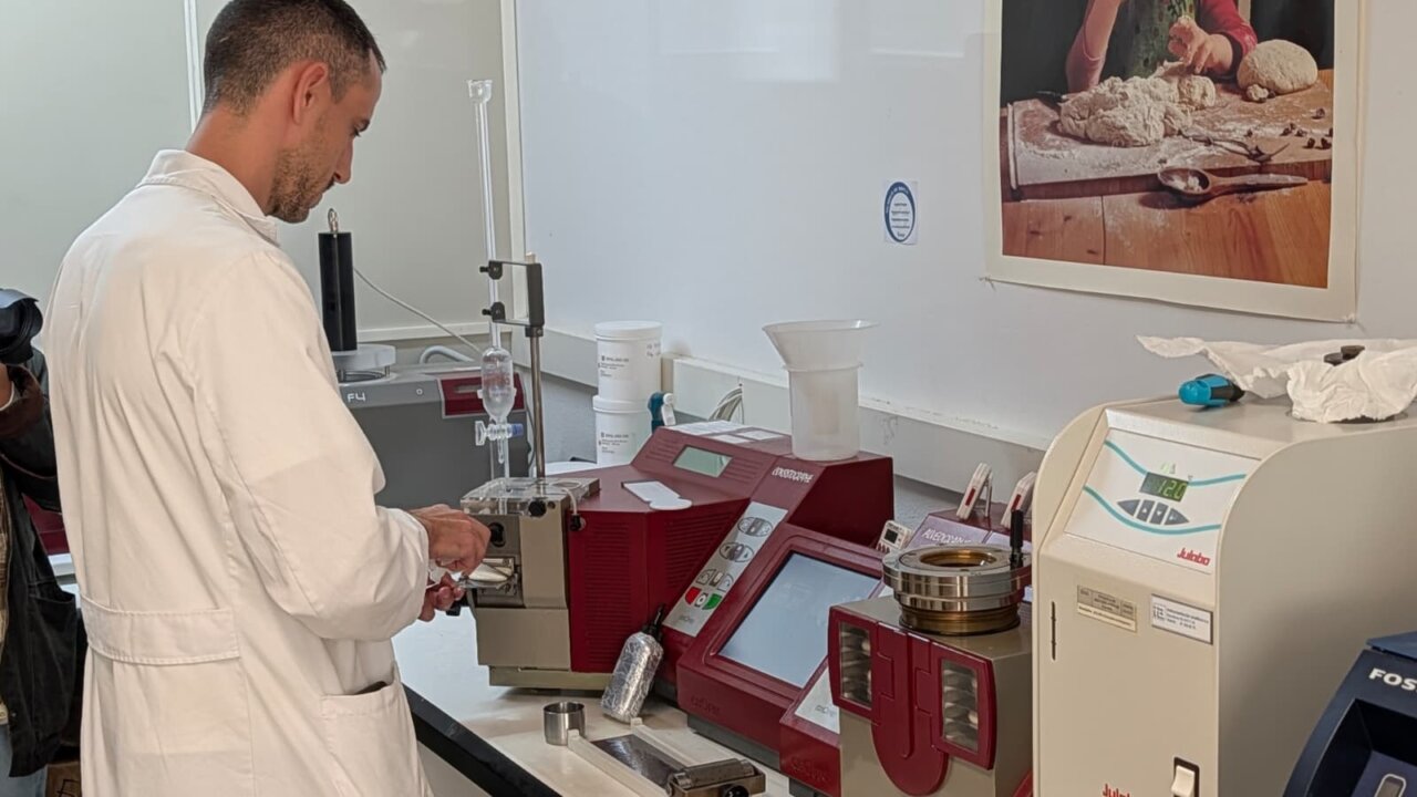 Una persona con bata blanca manipula equipos de laboratorio junto a una mesa de trabajo.