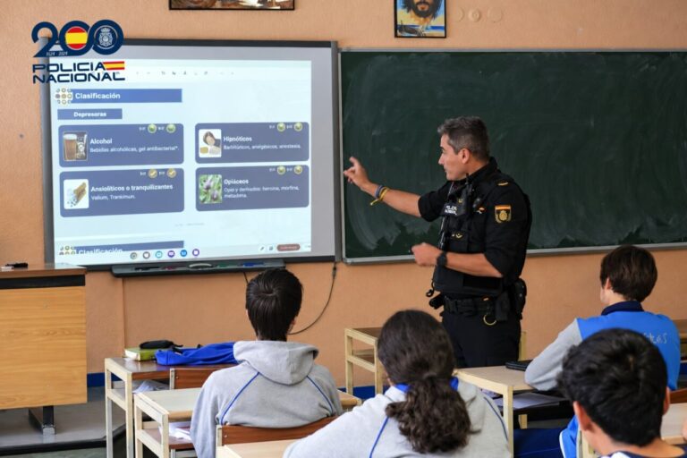 Una persona uniformada señala una diapositiva sobre sustancias ante alumnado sentado en un aula.