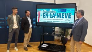 Tres hombres junto a una pantalla con el anuncio de Convivencias en la Nieve 2027.