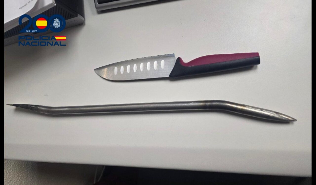 Un cuchillo de cocina y una barra metálica alargada sobre una mesa blanca.