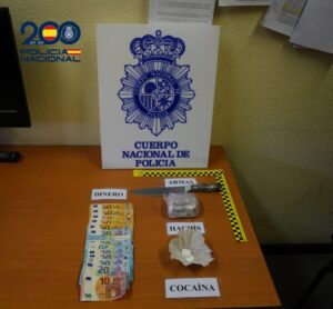 Fotografía de dinero, un cuchillo y paquetes etiquetados como hachís y cocaína