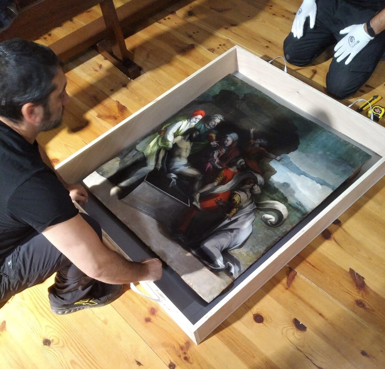 Hombre embalando la obra El Santo Entierro en una caja de transporte