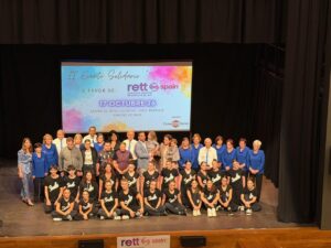 Grupo de participantes posa en el escenario bajo el cartel del evento solidario.