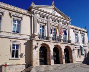Fachada del Ayuntamiento de Palencia con varias banderas y cielo despejado