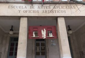 Entrada de una escuela de artes con columnas y una puerta roja decorativa