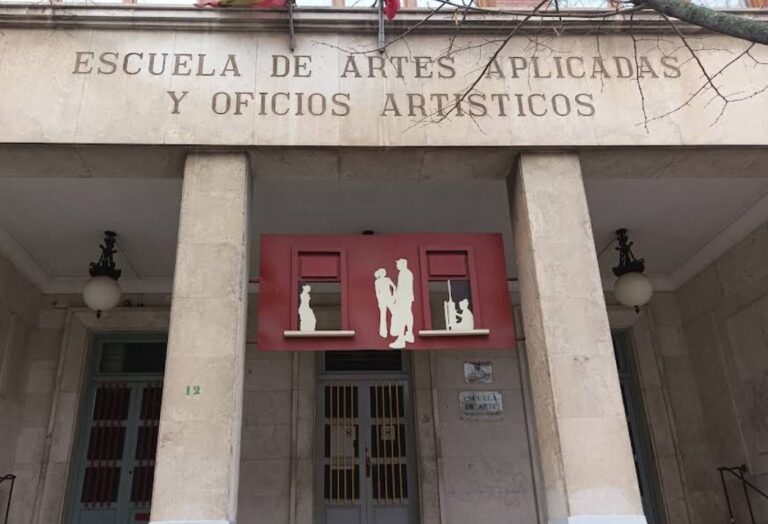 Entrada de una escuela de artes con columnas y una puerta roja decorativa