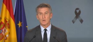 Alberto Núñez Feijóo habla ante dos micrófonos, con las banderas española y europea detrás.