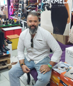Hombre sentado en una zapatería con calzado en exhibición