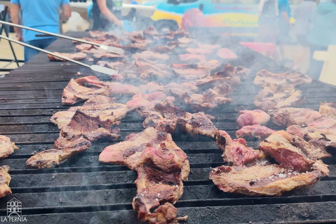 Trozo de carne asándose sobre una parrilla mientras varias personas la atienden