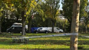 Furgonetas policiales y cinta de seguridad en una zona arbolada.