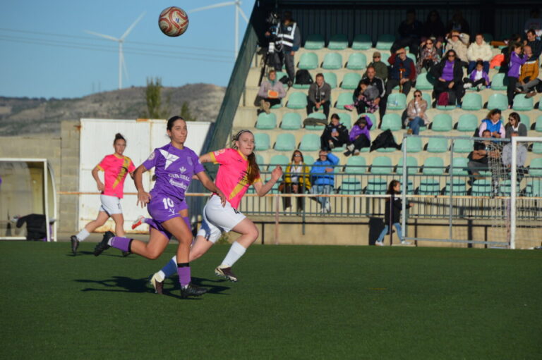 Dos futbolistas disputan el balón durante un partido de fútbol femenino.