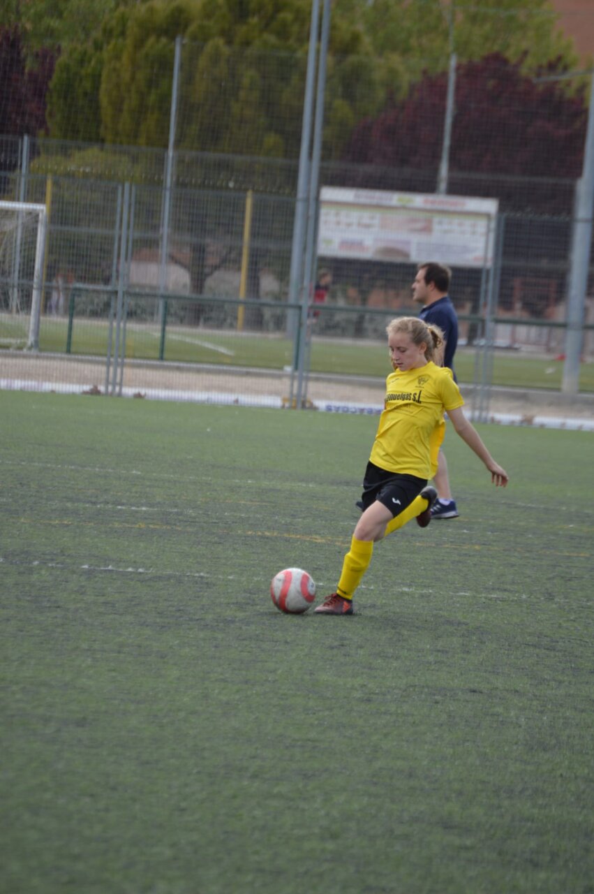 Futbolista con camiseta amarilla golpea un balón en un campo de fútbol