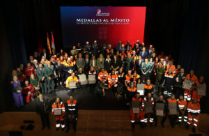 Grupo de asistentes posa con uniformes y diplomas ante el escenario de Protección Civil.