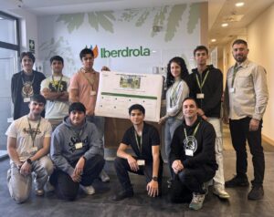 Grupo de jóvenes posa con un cartel frente al logotipo de Iberdrola.