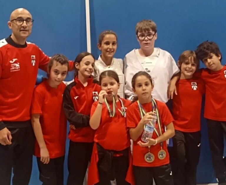 Grupo de karatecas posa con ropa deportiva; varios llevan medallas al cuello.
