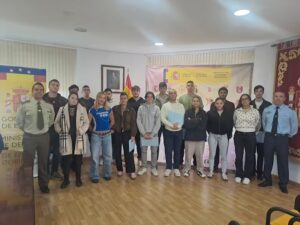 Varias personas posan en una sala ante carteles institucionales de Defensa en Palencia.