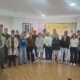 Varias personas posan en una sala ante carteles institucionales de Defensa en Palencia.