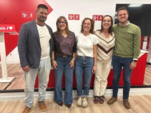 Cinco personas posan frente a paneles con los logotipos del PSOE de Palencia.