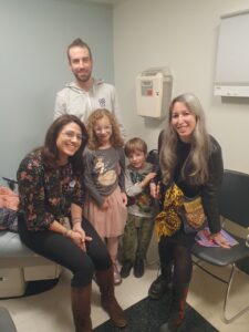 Cinco personas posan juntas en una sala con equipo médico y sillas.
