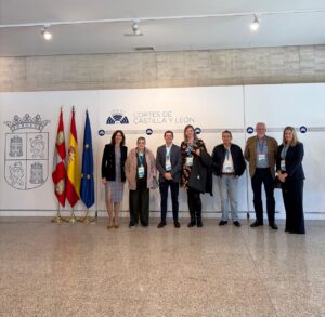 Grupo de siete personas posa junto a los emblemas de las Cortes de Castilla y León.