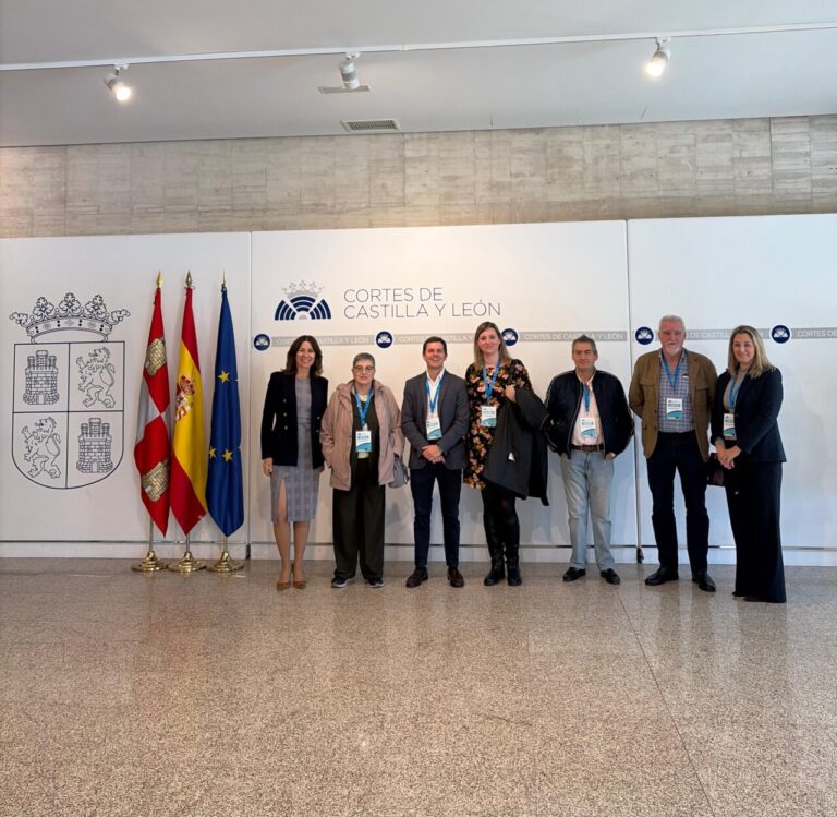 Grupo de siete personas posa junto a los emblemas de las Cortes de Castilla y León.