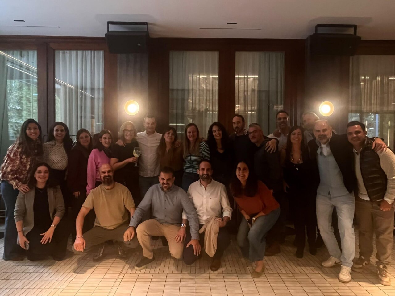 Grupo de adultos posa junto en un espacio interior durante una reunión.