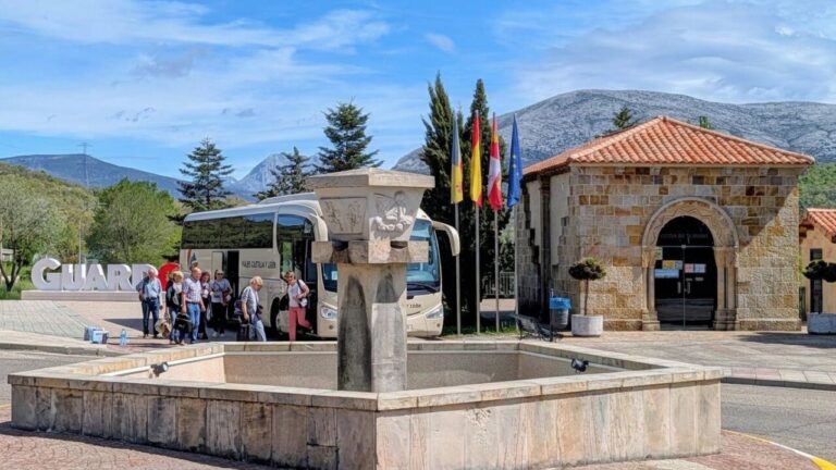 Grupo de turistas en Guardo junto a una fuente y un autobús