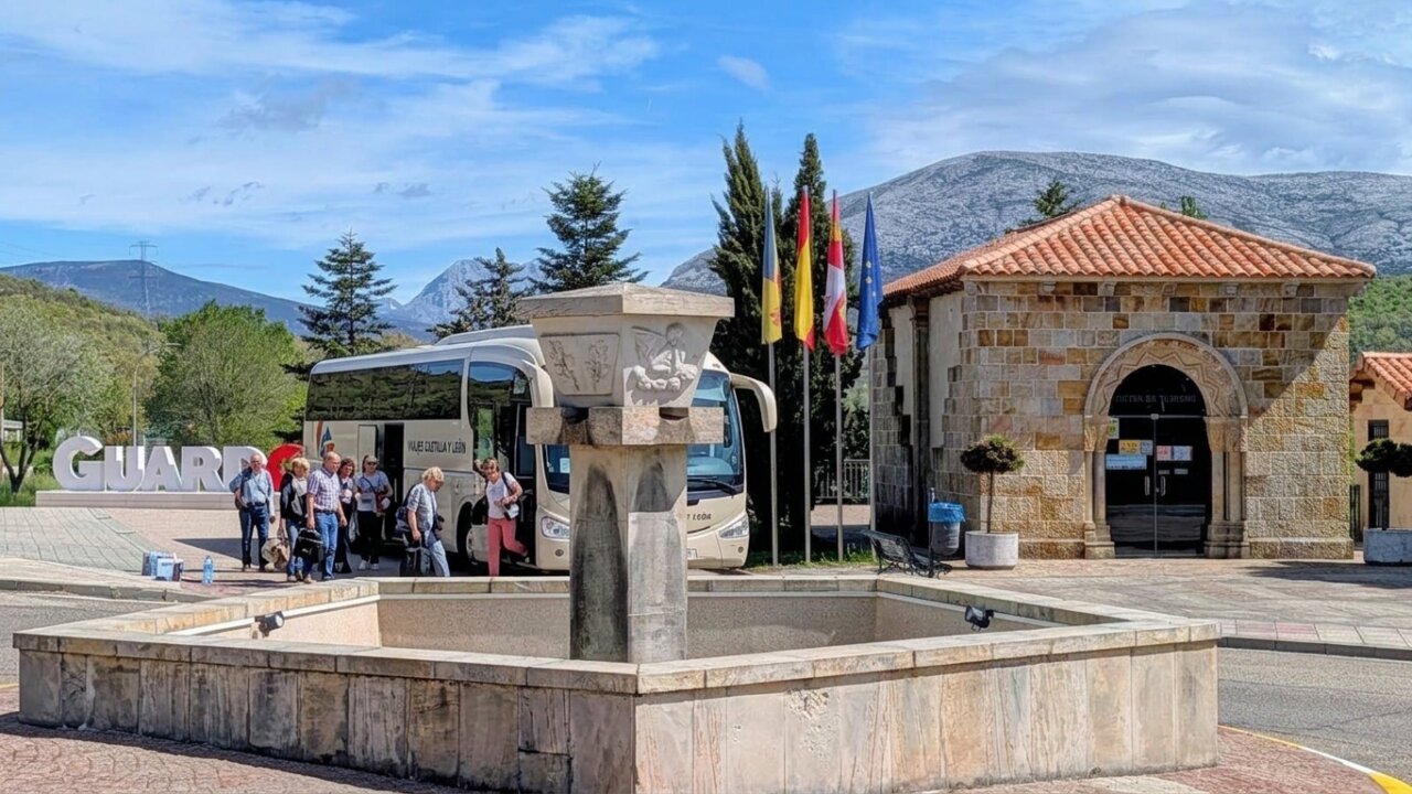 Grupo de turistas en Guardo junto a una fuente y un autobús