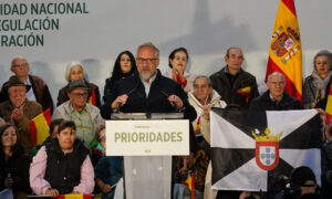 Un hombre habla desde un atril de Vox ante un público con banderas