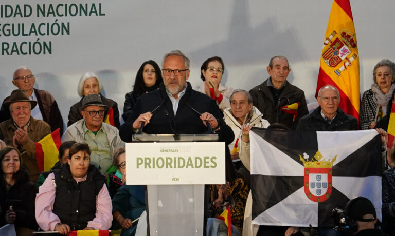 Un hombre habla desde un atril de Vox ante un público con banderas