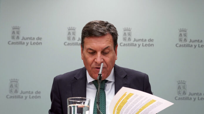 Hombre sentado ante un micrófono lee un documento frente al logotipo de la Junta.