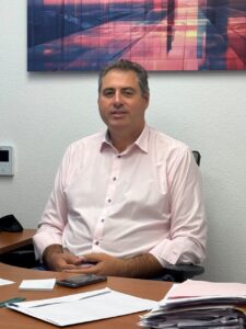 Hombre sentado ante un escritorio con documentos y un teléfono móvil.
